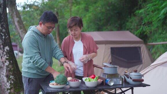 周末早上亚洲华人夫妇在露营帐篷旁准备早餐