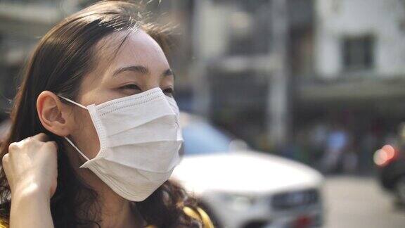 年轻的亚洲妇女咳嗽用口罩保护城市道路上的空气污染