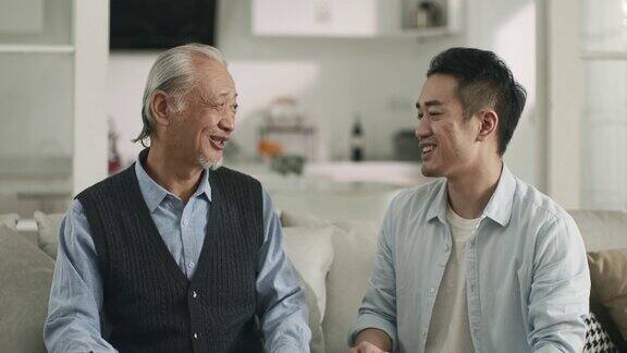 年长的亚洲父亲和成年的儿子在家里聊天