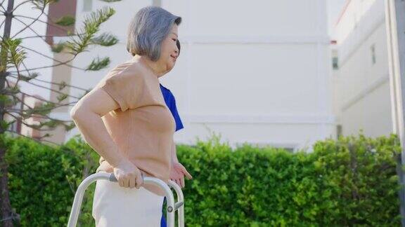 一位亚洲残疾老年妇女在绿色公园与行人一起慢步行走老年的成年病人残障女性下午在花园里进行物理治疗医疗保险