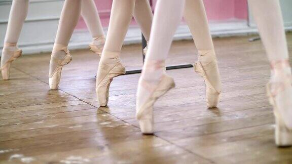 在芭蕾舞大厅里年轻的芭蕾舞演员们穿着尖头鞋踮起脚尖表演pasechappe特写镜头