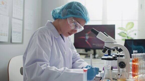 亚洲女性医学研究科学家在实验室通过显微镜观察