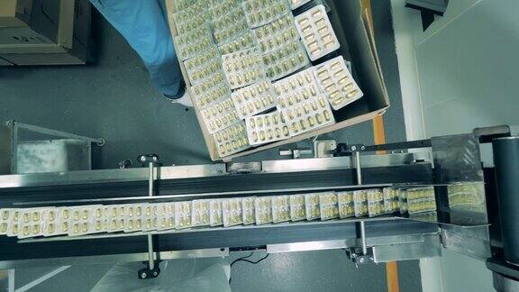 工厂工人正在把泡满水泡的胶囊装进盒子里制药公司生产杀毒药