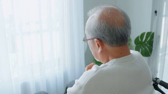 亚洲老年男性退休后独自坐在轮椅上呆在家里不快乐的老年残疾人感到孤独和担心卫生保健问题医院保健和医疗理念