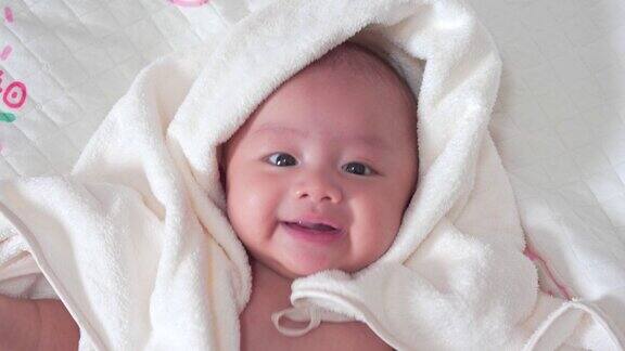 可爱的亚洲新生儿躺在床上白色的毯子在卧室小男孩看着镜头笑着开心的脸天真的小婴儿刚出生的第一天母亲一天