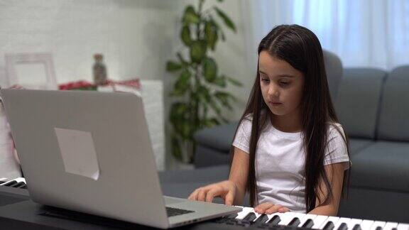 可爱的小女孩在钢琴上弹奏着圣诞装饰的背景大流行期间的圣诞节庆祝活动