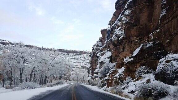 在冬天沿着一条道路行驶穿过一个多雪的丘陵的沙漠景观