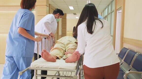一组医生、护士和外科医生在医院走廊抬着躺在担架上的重伤病人医护人员急忙将急诊老病人转移到手术室