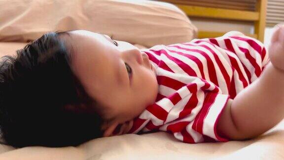 可爱的亚洲小男孩的肖像穿着红白条纹衬衫吮吸手指