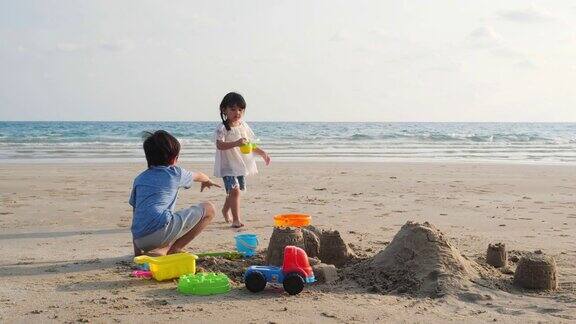 亚洲小孩弟弟和妹妹一起在海滩上玩堆沙夏天在度假家庭、旅行和关系4k决议