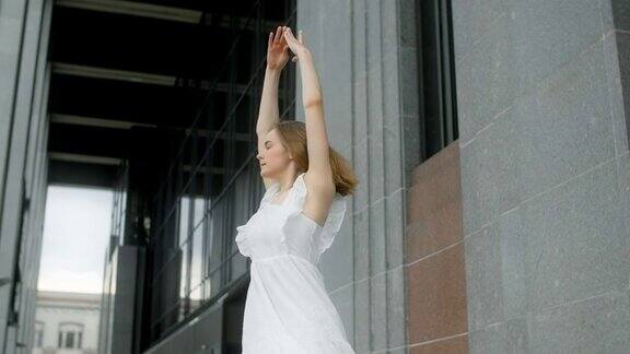 年轻的芭蕾舞女演员穿着白色的衣服在楼阁建筑群的画廊里旋转慢动作芭蕾舞女演员在户外跳舞4k120帧每秒