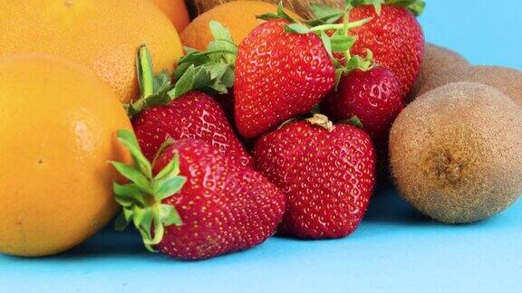 近距离接触新鲜的有机草莓橙子和猕猴桃在蓝色的背景