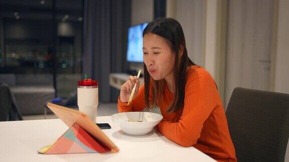 4K亚洲女人晚餐吃中餐在平板电脑上看电影