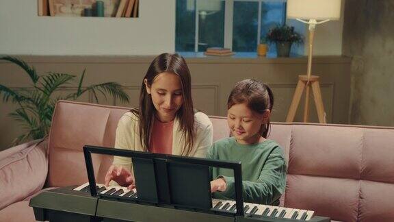 亚洲母女用平板电脑学习弹钢琴