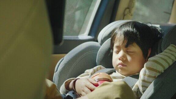 小男孩睡在车里的安全座椅上