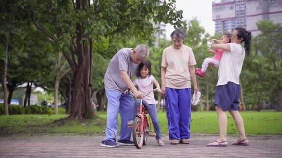 亚洲的祖父母教孙子骑自行车与家人一起散步和锻炼