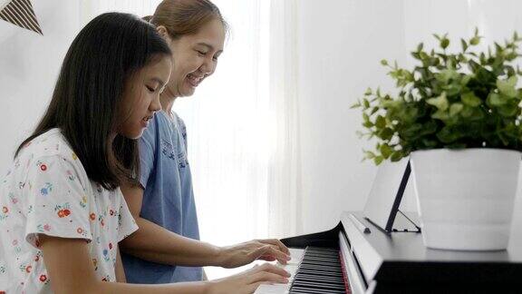 亚洲女孩和她的母亲弹钢琴的慢镜头缩小