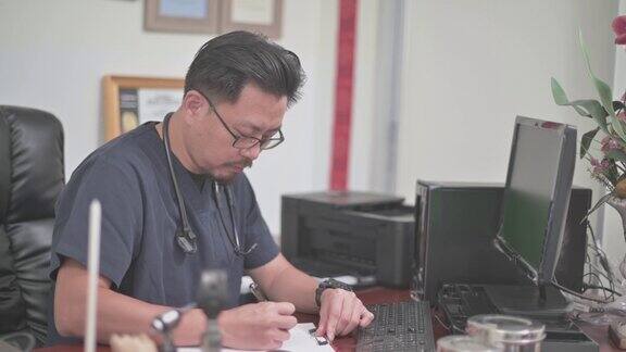 亚洲华人中年男性医生在桌面电脑上查看病人记录