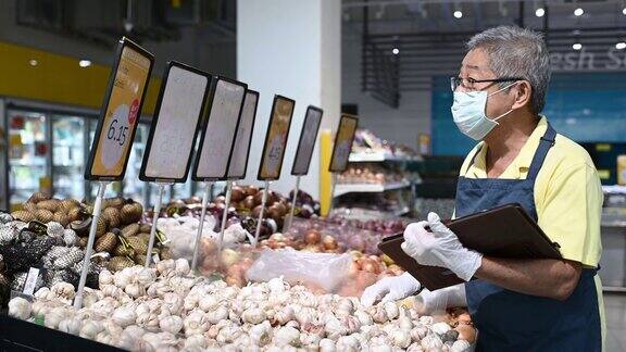 一名亚洲华人高级男子超市店主零售助理戴着口罩