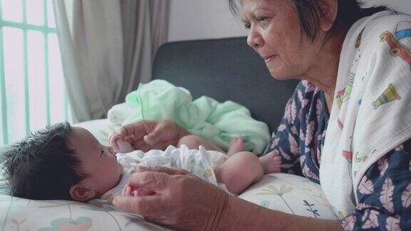 亚洲快乐奶奶在家里玩耍和照顾新生儿