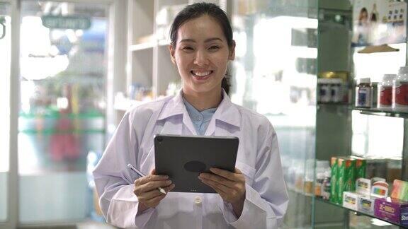 一个微笑的亚洲女性药剂师站在柜台后面的肖像