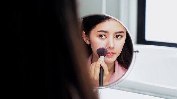 一个亚洲女人在浴室镜子前化妆