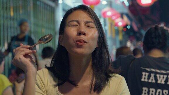 泰国曼谷夜市年轻的亚洲女性朋友在街头享受街头小吃假日度假旅行