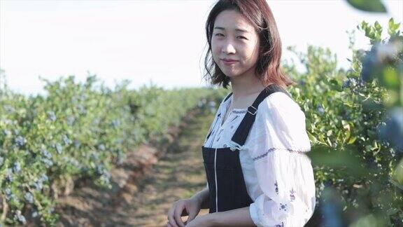 亚洲妇女在蓝莓农场微笑