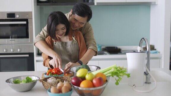 亚洲华人丈夫教妻子在厨房切蔬菜
