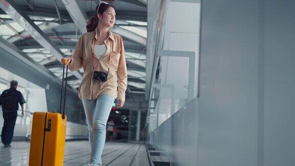 幸福微笑的亚洲女乘客带着黄色行李箱走在机场候机楼女乘客在前往航班登机口的路上旅游旅行