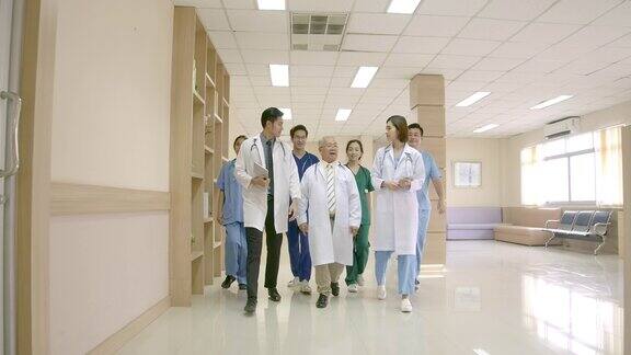 一群亚洲男女医务工作者和资深医生在医院走廊边走边谈