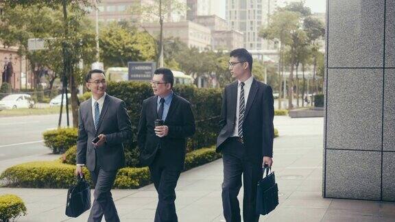 三个亚洲商人在街上散步和交谈