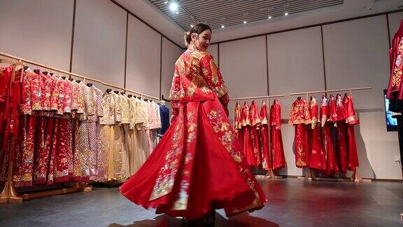 年轻的中国新娘纺纱在美丽的红色和金色婚礼群瓜