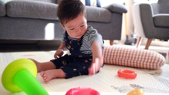 小男孩在客厅里玩耍坐在家里地板上的婴儿安全软垫子上