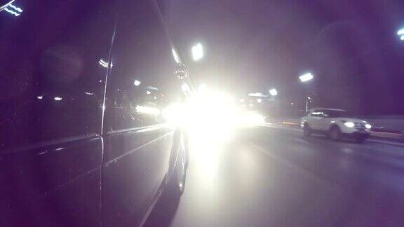 快速城市驾驶夜间道路POV通过城市在夜间时间推移左侧的汽车低角度的观点相机拍摄回来