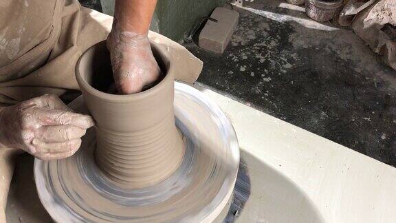 亚洲华人高级陶艺师在他的工艺工作室里在一个旋转的陶轮上制作陶器