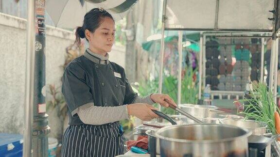 亚洲女厨师在曼谷街头市场烹饪美味的泰式炒粉