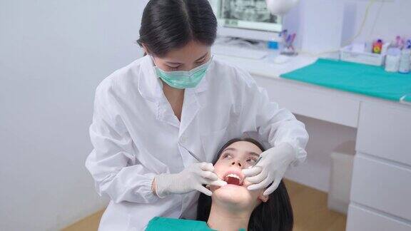 亚洲年轻牙医戴上口罩使用医疗器械进行口腔护理检查医生检查蛀牙和牙龈疾病牙科诊所的医疗职业服务和保健