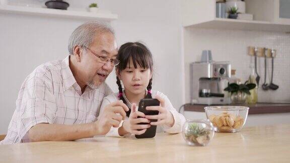 家里的爷爷和孙子在家里用手机玩社交媒体