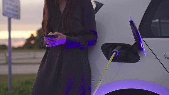 一个无法辨认的女人在用她的智能手机给汽车充电