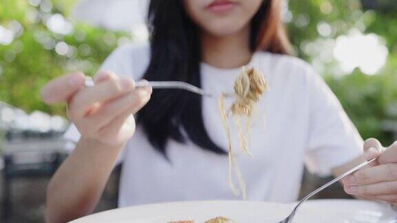 亚洲少女喜欢在家里的花园里吃美味的意大利面对外卖食物的味道感到满意周末活动快乐餐厅生活理念