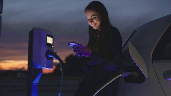 一名年轻女子在等待汽车充电时使用智能手机