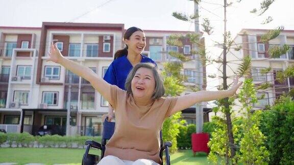 护理人员推着坐在轮椅上的老年病人在外散步