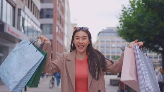图为亚洲女性在百货公司户外购物迷人的年轻女孩拿着购物袋看着镜头快乐地走在购物中心购物