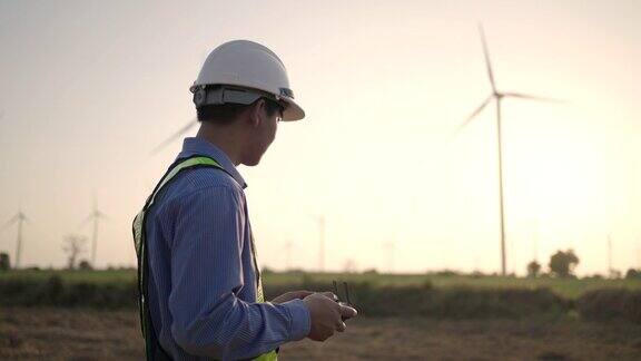 年轻男性工程师控制无人机在亚子集的风力发电站工作