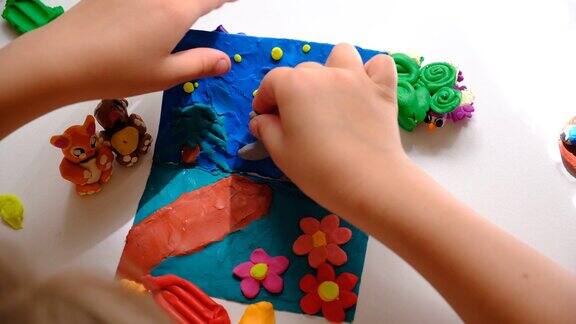 孩子在硬纸板上涂上彩色橡皮泥用卡通动物制作童话卡片
