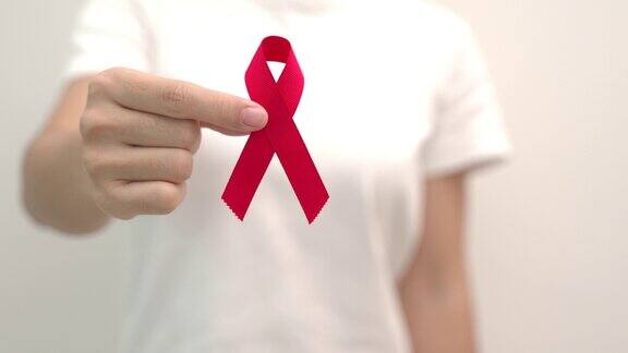手握红丝带纪念12月的世界艾滋病日、获得性免疫缺陷综合征、多发性骨髓瘤癌症宣传月和全国红丝带周保健和世界癌症日