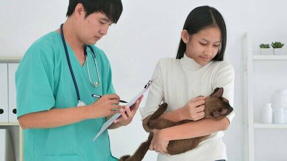 微笑肖像亚洲少女与宠物和亚洲男子兽医看在诊所的相机采购产品兽医关系人保健和医学宠物爱
