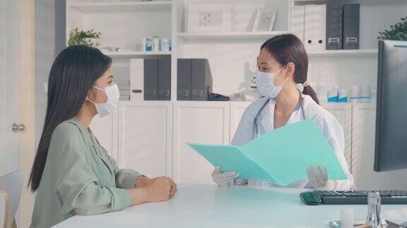 亚洲专科女医生向小女孩病人讲解诊断专业女医生佩戴口罩使用笔记本电脑并在预约就诊时向住院的患者提供治疗方案