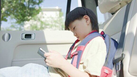 一个可爱的小男孩在汽车后座上使用数码平板电脑